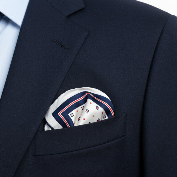 A square white scarf with a navy blue border and a repeating red and navy geometric pattern, laid flat on a white surface.