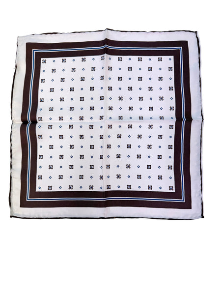 A square white scarf with a dark brown border, featuring a repeating geometric pattern of black squares and blue dots, laid flat on a white surface.